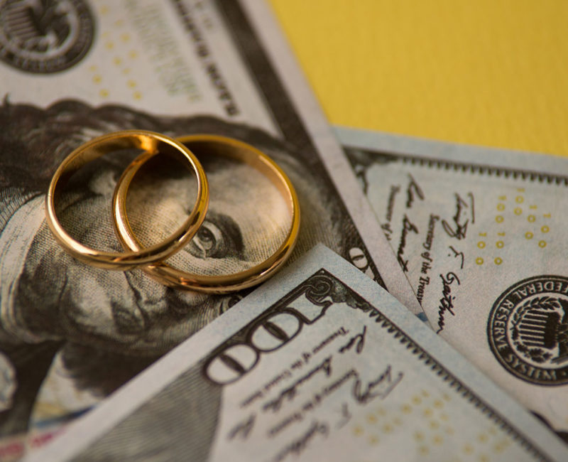 two wedding rings sit on top of cash