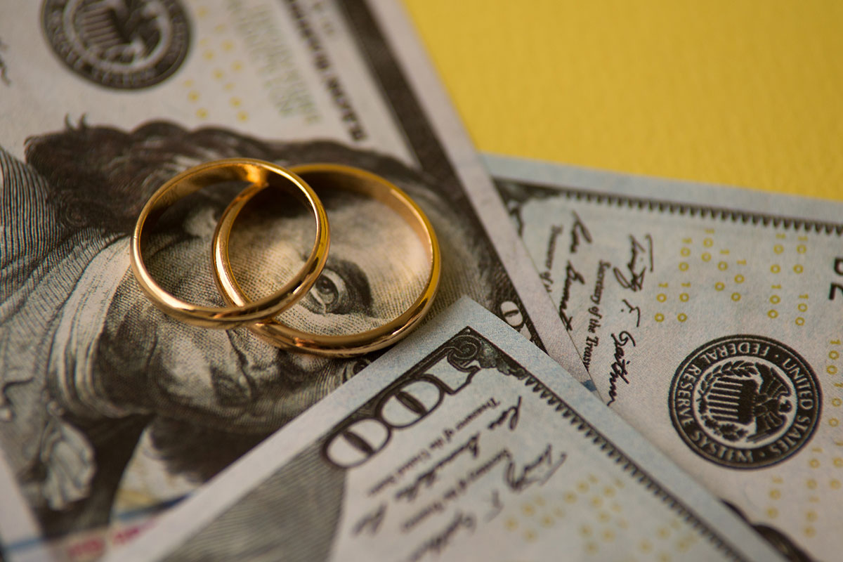 two wedding rings sit on top of cash