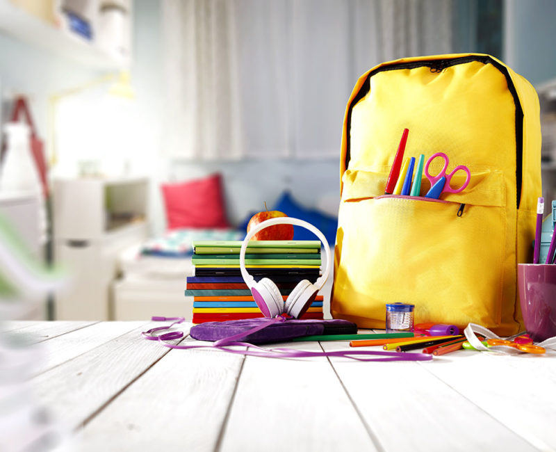 child's backpack sits on top of a table next to school supplies