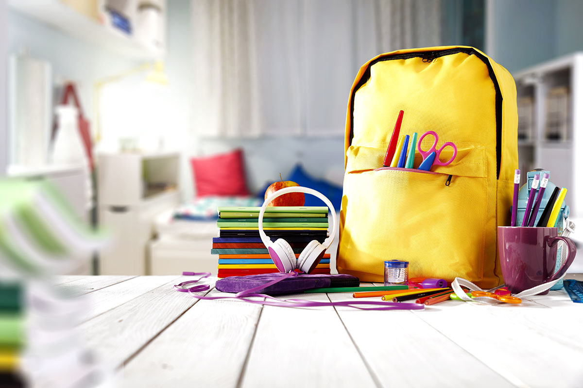 child's backpack sits on top of a table next to school supplies